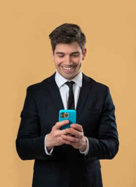 Akıllı telefondan internette sörf yapan yakışıklı bir erkek. Sarı arka planda gülücük ve neşe dolu bir adam. Teknoloji, başarı, mutluluk, sosyal ağ konsepti. Yüksek kalite