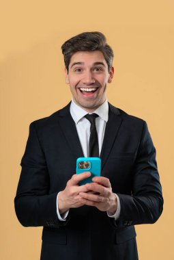 Akıllı telefondan internette sörf yapan yakışıklı bir erkek. Sarı arka planda gülücük ve neşe dolu bir adam. Teknoloji, başarı, mutluluk, sosyal ağ konsepti. Yüksek kalite