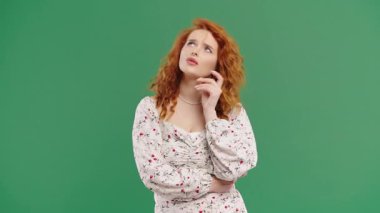 Yeşil elbiseli, kızıl saçlı, kıvırcık bir kadının yanında düşünceli. Şaşırmış Kadın Bakışlı Cevap