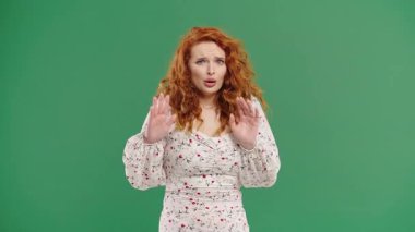 Genç model bir şeyden korkarak şok geçirdi ve yeşil arka planda korku dolu büyük gözlerle kameraya doğru bağırdı. Fobi, sorun, panik konsepti. Yüksek kalite 4k görüntü