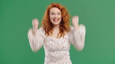 Kendine güvenen kumral saçlı kadın başarıyı enerjik bir yumruk pompası ve ışıltılı bir gülümsemeyle kutluyor. Başarı, duygusal kazanç, motivasyon, ilerleme, kadın gücü