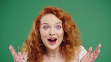 Şaşkın, kızıl saçlı kadın, vay canına diyor, inanamıyorum. İlgi çekmeye çalışan etkileyici bir bayan. Satış kavramı, karlı bir teklif. Yeşil arka planda heyecanlı öğrenci kız. Yüksek kalite 4k