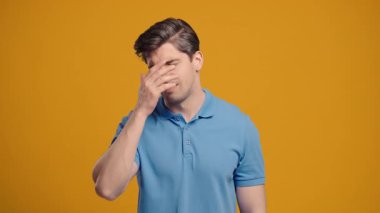 Hayal kırıklığına uğramış mavi elbiseli adam facepalm yapıyor. Pişmanlık, başarısızlık, tatminsizlik, boşa geçen zaman, hayattaki sorunlar, sarı stüdyo geçmişi. Yüksek kalite 4k