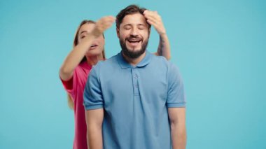 Pretty Woman, sürpriz yapmadan önce sevgilisinin gözlerini kapatıyor. Mavi stüdyo geçmişinde mutlu bir çift. Aşk, tatil, mutluluk konsepti. Yüksek kalite 4k