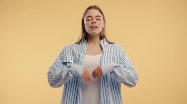 Sakin bir kadın dinleniyor, meditasyon yapıyor, stresi reddediyor. Kadın derin nefes alıyor, sakinleşiyor, bej renkli stüdyo arka planı. Yoga, ahlaki denge, zen konsepti. Yüksek kalite