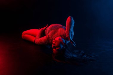 Vücudu yerde kıvrak hareketlerle dans eden kadınları cezbediyor. Karanlık stüdyoda neon ışıklı erotik danslar. Dar elbiseli ve topuklu ayakkabılı bayan dansçı. Yüksek kalite fotoğraf