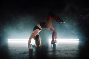 Vücudu yerde kıvrak hareketlerle dans eden kadınları cezbediyor. Karanlık stüdyoda neon ışıklı erotik danslar. Dar dantelli ve topuklu ayakkabılı bayan dansçı. Yüksek kalite fotoğraf