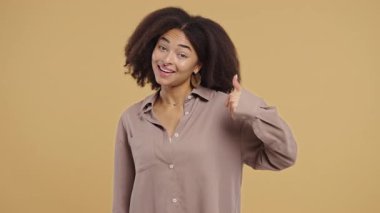 Zarif afro-amerikan ergen kız, el işaretli, baş parmak hareketi gibi. Mutlu bayan, doğru seçim, harika bir anlaşma, bej arka plan. Pozitif kadın model kameraya gülümsüyor