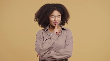 Genç kadın melez model sakin yüzüyle parmaklarını dudaklarına dayayıp sessizlik istiyor. Gizlilik, dedikodu, söylentiler, odaklanma, mahremiyet, sınırlar, ifade içeriğindeki sessiz iletişim