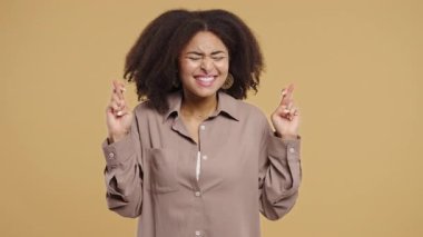 Afro-Amerikan güzel genç kız dua ediyor, ondan özür diliyor, o suçlu. Bej arka plan. Umut dolu dua eden bayan birinden arzularını tatmin etmesini ve yardım etmesini istiyor. Yüksek kalite 4k