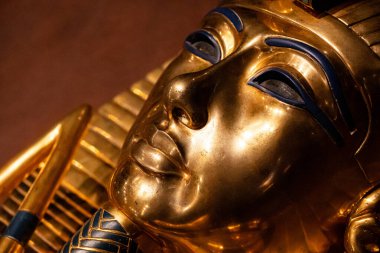 Altın antik Mısır cenaze maskesinin detaylı görüntüleri. Karmaşık tasarım, cilalanmış metal, zengin tarihi miras..