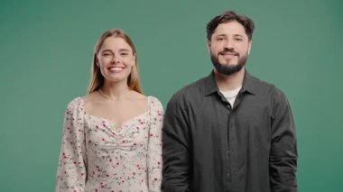 Güzel bir kadın ve Amerikalı bir erkek. Mutlu çift, pastel yeşil arka plan. Olumlu arkadaşlar kameraya gülümser, güven ve aşk kavramı.