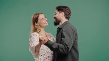 Romantik bir randevu. Birbirlerine aşık, yakın dans eden, gülümseyen, yeşil stüdyo geçmişinde el ele tutuşan bir çift. Mutlu ortaklar. Yüksek kalite 4k görüntü