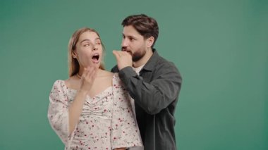 Dedikoducu adam kadınların kulağına fısıldıyor. Dedikodular, dedikodular, yeşil stüdyo. Güzel bayan ve yakışıklı adam. Komplo konsepti. Yüksek kalite 4k