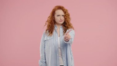 Parmak işaretini onaylamayan ilgisiz genç bir kadın. Benimle oynama, bu kadar yeter. Pembe arka planda kızıl saçlı kadın portresi. Yüksek kalite 4k