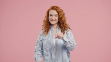 Güzel bir kadın elleriyle kalp şekli oluşturur, sevgi gönderir. Pembe arka planda hoş bir bayan. Kadın sağlığı, gönüllülük, bağış, minnettarlık sembolü, flört. Yüksek kalite 4k