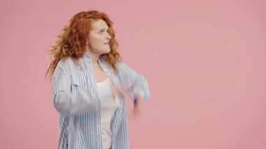 Stres ve öfke içinde bir kadın, saldırganlıkla tehdit ediyor, bağırıyor ve pembe kameraya bakıyor. Öfkeli kızıl saçlı Amerikalı kadın. Çatışma, tartışma, stres, duygusal patlamalar. Yüksek kalite 4k görüntü