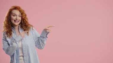 Gülümseyen 30 'lu yaşlardaki bayan reklam için boş bir yer arıyor. Önerilen kadın sol tarafı işaret ediyor, kopyala alanı. Kadın, pembe arka planda izole edilmiş bir şey sunuyor. Yüksek kalite