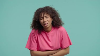 Afrikalı kadın elleriyle karnını sıkıyor. Karın ağrısı, karın ağrısı, karın ağrısı. Sağlık sigortası, regl dönemindeki kramplar ya da bağırsak gazı konsepti. Yüksek kalite 4k