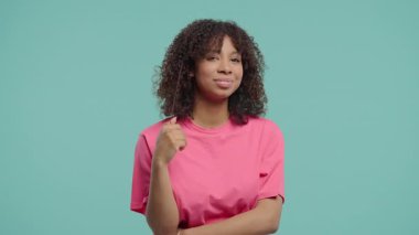 Neşeli Afrikalı Kadın Gülümsüyor, Mavi Stüdyoda Kameraya Flört Ediyor. Çekici trend kızı muhteşem kıvırcık saçlarını düzeltiyor. Yüksek kalite 4k görüntü