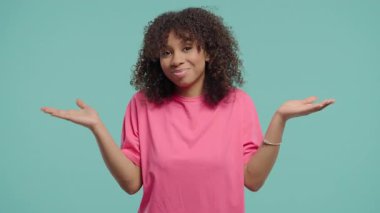 Güzel, genç bir kadın, omuzları yukarıda, yardımcı olamıyor, bilmiyorum jestler yapıyor. Zor soru, suçlu tepkisi, mavi arka planda. Yüksek kalite 4k