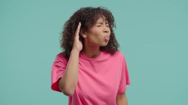 Doğal bukleleri olan genç bir kadın, işitme sorunu ya da kulak hizasıyla ilgili kafa karışıklığına işaret ediyor. Ses sorunları, dikkat ipuçları, iletişim eksikliği, sesle ilgili görseller için mükemmel.