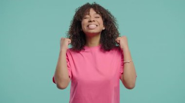 Kendine güvenen kıvırcık saçlı kadın başarıyı enerjik bir yumruk pompası ve ışıltılı bir gülümsemeyle kutluyor. Başarı, duygusal kazanç, motivasyon, ilerleme, kadın gücü