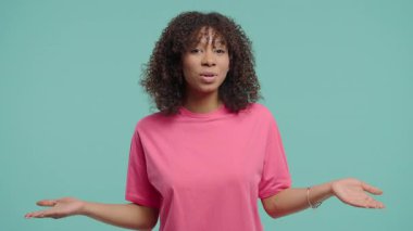 Kıvırcık saçlı kendine güvenen kadın konuşmacı, kameradaki bir şeyi anlamlı el hareketleriyle açıklıyor. Çevrimiçi dersler, sosyal medya içeriği, vloglama, dersler veya webinarlar
