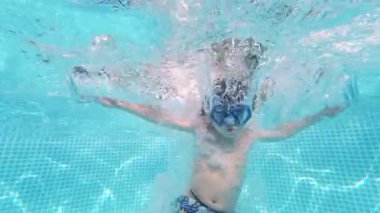 Mutlu küçük çocuk havuza dalıyor mavi berrak su, çocuklar için eğlence. Yaz yüzüşü, sualtı eğlencesi. Komik çocuk, dalmanın tadını çıkar. Aşırı açı. Yüksek kalite 4k görüntü