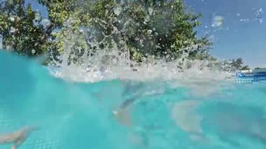 Mutlu küçük çocuklar havuza dalıyor mavi berrak su, çocuklar için eğlence. Yaz yüzüşü, sualtı eğlencesi. Komik çocuklar, dalmanın tadını çıkarın. Aşırı açı. Yüksek kalite 4k görüntü