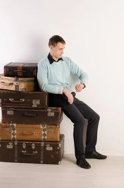 Young Man Leans Stack Suitcases Looks His Watch Light — Stock Photo, Image