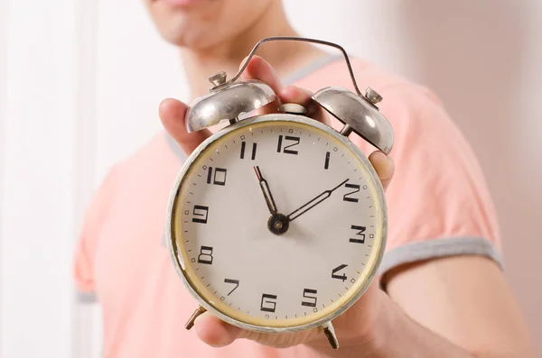 old vintage alarm clock, in the hands of a man, in a pink t-shirt