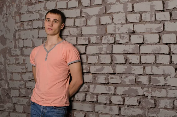 一个穿着粉色T恤的年轻人站在灰色的砖墙旁边的画像 文字的空间 — 图库照片