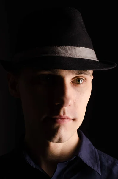 一个戴着礼帽的年轻人的画像 带着丝带 背景是黑色的 画室光 — 图库照片