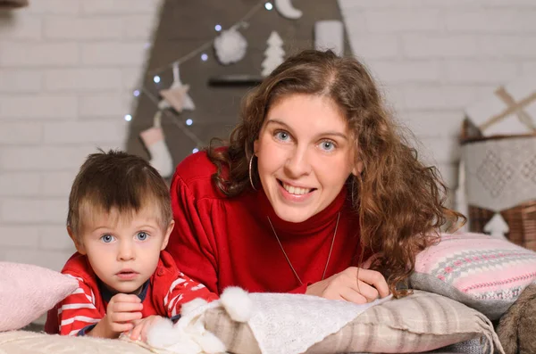Kırmızı Elbiseli Anne Oğul Yastıklarda Yere Yatın Noel Süslemelerinin Arka — Stok fotoğraf