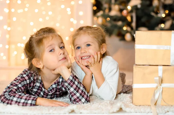 美しい幸せな笑いの妹 床に横たわって 部屋のクリスマスのインテリアの背景に 贈り物 夢の箱の横にある — ストック写真