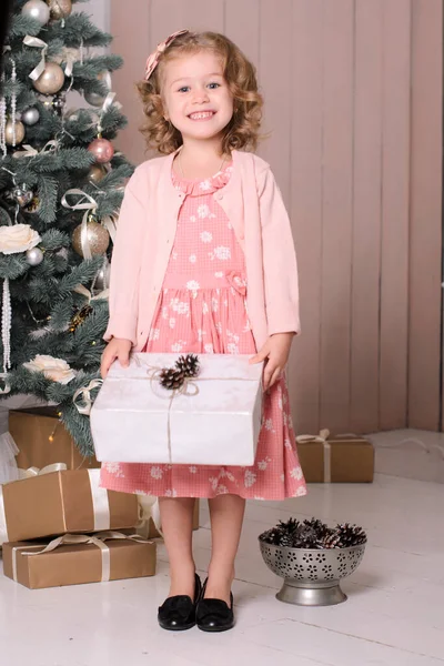 站在圣诞树下 身穿粉色衣服 手里拿着一个白色礼品盒的漂亮姑娘 — 图库照片