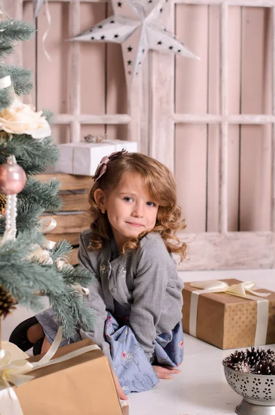 Egy Gyönyörű Mosolygós Lány Padlón Játékosan Kukucskál Díszített Karácsonyfa Mögül — Stock Fotó
