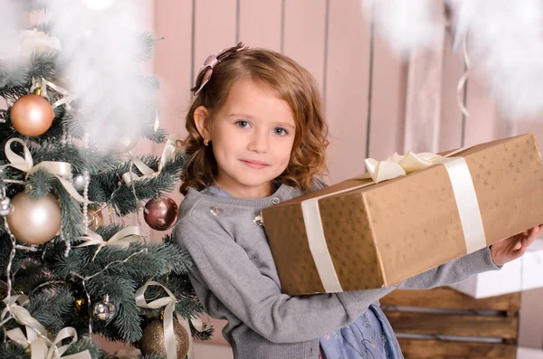 漂亮的微笑的女孩 手里拿着一个大礼品盒 用带子捆着 靠近圣诞装饰 — 图库照片