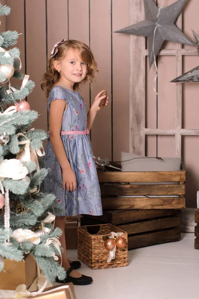 美丽的微笑的女孩 穿着蓝色的舞会礼服 靠着圣诞树 靠着一堵木制的墙 — 图库照片
