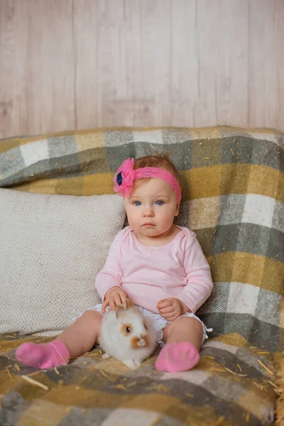 温柔的小女孩坐在一张格子毛毯上 亲切地抚摸着雪白的兔子柔软的毛皮 — 图库照片