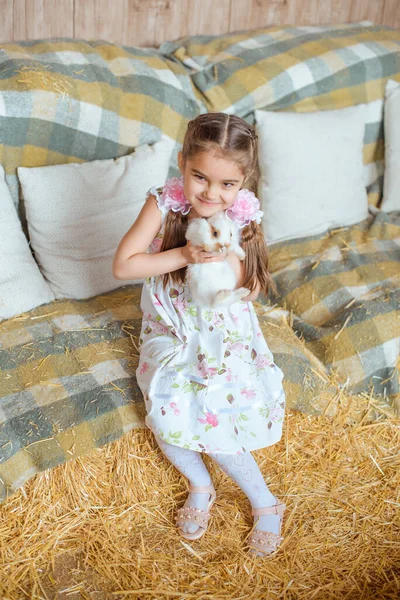 머리에 개달린 소녀는 담요로 덮인건 초더미를 배경으로 토끼를 — 스톡 사진