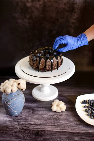 Egy Kéz Egy Kék Kesztyű Díszíti Áfonyával Egy Csokoládé Cupcake — Stock Fotó