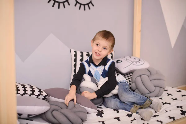 Ένα Αγόρι Καθημερινά Ρούχα Γιλέκο Και Τζιν Κάθεται Ένα Κρεβάτι — Φωτογραφία Αρχείου