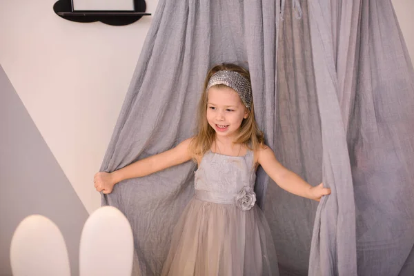 Mutlu Gülen Kız Odada Asılı Bir Çadırın Perdelerinden Dışarı Bakıyor — Stok fotoğraf