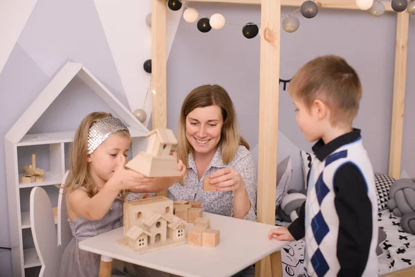 Uma Mulher Mãe Educadora Professora Observa Como Crianças Brincam Com Imagem De Stock