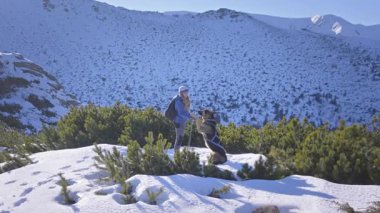 Karların arasında karlar içinde yürüyen köpekli bir kız. Dağlarda kış yürüyüşü. Dağlardaki maceralar