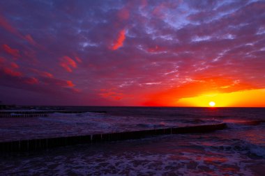 Baltık Denizi kıyısında gün batımında ahşap dalgalı sular