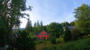 Dağlarda bir ev, yeşil bir ormanın arka planına karşı hava koşulları değişken.