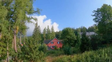 Dağlarda bir ev, yeşil bir ormanın arka planına karşı hava koşulları değişken.